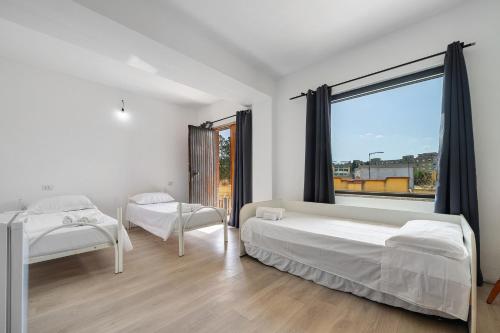 a bedroom with two beds and a large window at Daluef Alloggi in Assemini