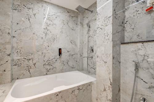 a bathroom with a white tub and marble walls at The Grand Olive Aero Suites Near Delhi Airport in New Delhi