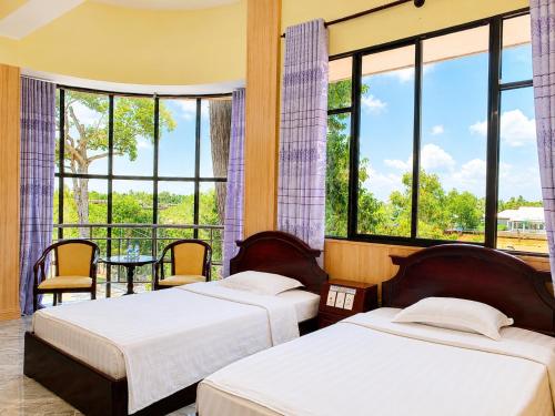 two beds in a room with large windows at Hung Vuong Hotel in Ben Tre