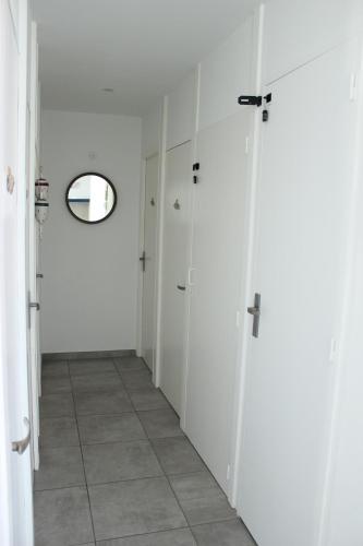 an empty hallway with white doors and a mirror at L'Augustémile au bord de l'eau in La Tranche-sur-Mer