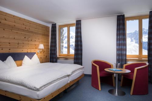 a bedroom with a bed and a table and chairs at 3100 Kulmhotel Gornergrat in Zermatt