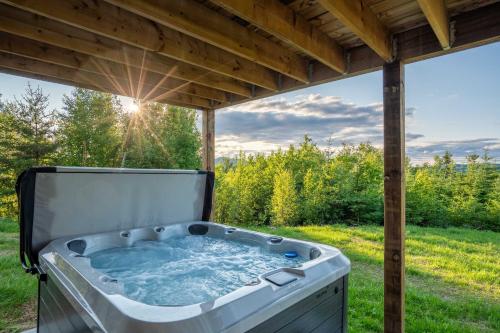 a hot tub under a pergola in a yard at Apex Nuage - Spa Game Room & Panoramic Views in Saint Come