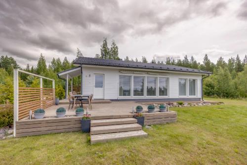a small white house with a deck and a table at Villa Vilkama 2 cabins Lake view, incl indoor hot tub, sauna in Laukaa
