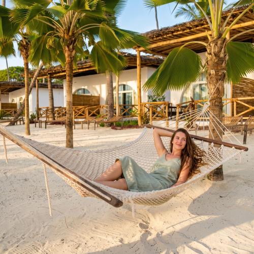 a woman laying in a hammock on a beach at Royal Mandarin Hotel & Resort Zanzibar in Pwani Mchangani