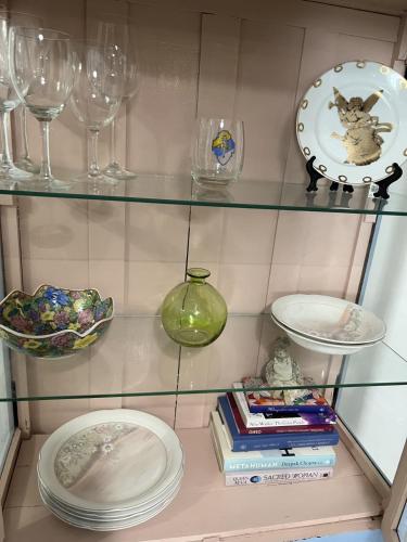 a glass shelf with plates and glasses and a clock at OJAS Local Nest in San Juan