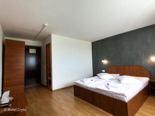 a bedroom with a large bed with white sheets at motel cryss in Ocna Sibiului