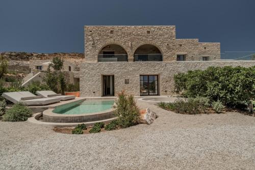 a stone house with a swimming pool in front of it at Eunoia Suites in Krotiri