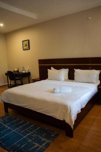 a bedroom with a large bed with white sheets at Skyblue GuestHouse in Lubumbashi