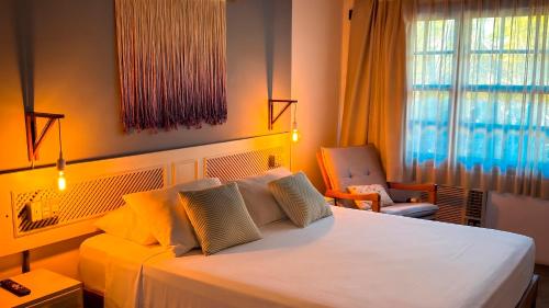 a bedroom with a large white bed and a chair at Praia Mole Hotel in Florianópolis