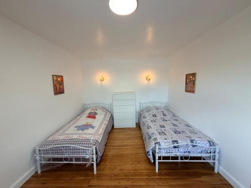 two beds in a room with white walls and wooden floors at Gite Maison Saint-Martin in La Groise