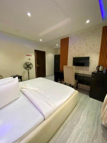 a bedroom with a large white bed and a desk at S&B Hotel in Agege