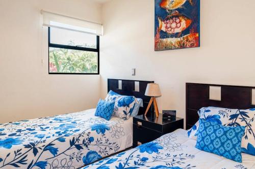 a bedroom with a bed with blue and white sheets and a window at Casa Villa Ensueño in Jacó