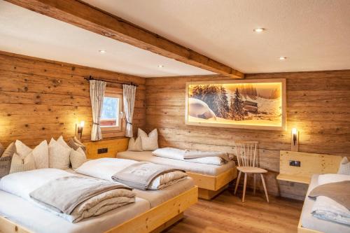 two beds in a room with wooden walls at Neuhaus Alm in Gerlosberg