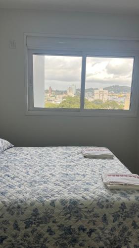 a bedroom with a bed with a large window at Gaudi in Santa Cruz do Sul