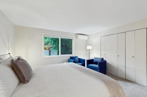 a white bedroom with a large bed and blue chairs at Sanctuary on Park Ave in Hawley