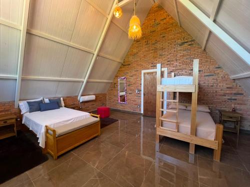 a bedroom with two beds and a brick wall at Cabaña Premium Yvyja de La Mala Junta in Atyrá