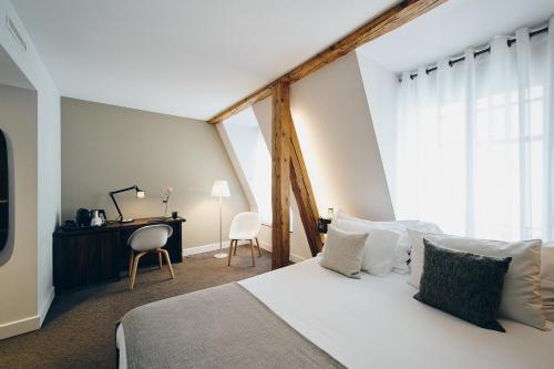a bedroom with a large white bed and a desk at Hôtel des Voyageurs Boutique in Lausanne