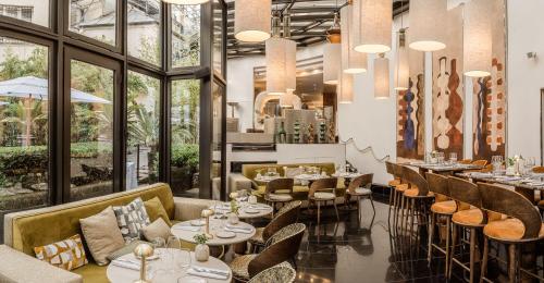 a restaurant with tables and chairs and large windows at Les Jardins Du Marais in Paris