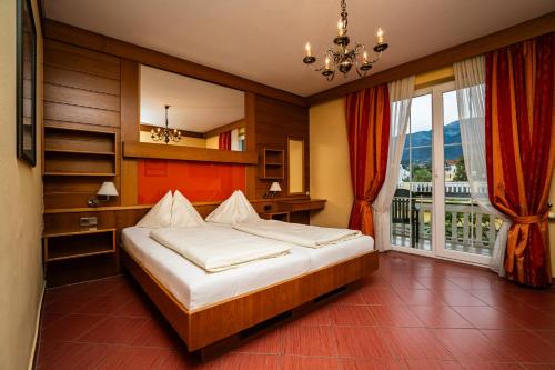 a bedroom with a bed and a large window at Seehotel Steiner in Seeboden
