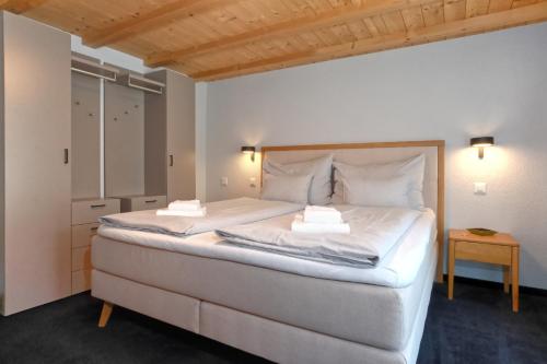a bedroom with a large white bed and a table at Chalet Eiger View - GRIWA RENT in Grindelwald