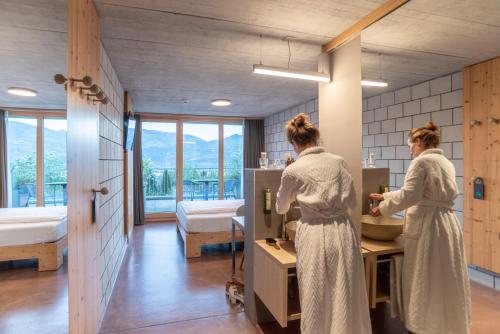 two women standing in a bathroom with a sink at Hotel Seaside in Spiez