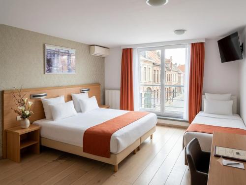 a hotel room with two beds and a window at Hotel Taormina Brussels Airport in Zaventem