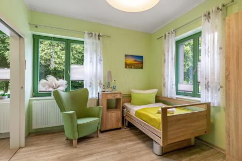 a bedroom with a bed and a chair and windows at Pension Pusteblume in Meyenburg