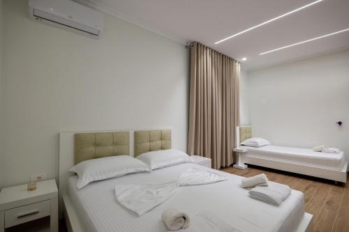 a white bedroom with a large bed and a tub at SulMare Rooms in Sarandë