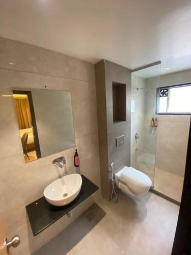 a bathroom with a sink and a toilet and a mirror at Hotel Banyan Crest in Solapur