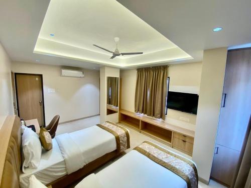 a hotel room with two beds and a flat screen tv at Hotel Banyan Crest in Solapur