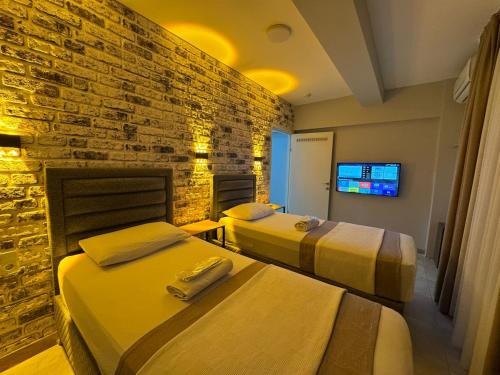two beds in a room with a brick wall at Silvercity Hotel&Suits in Eskisehir