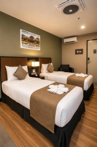 a hotel room with two beds with flowers on them at Hotel Valya Melaka Sentral Riverfront in Malacca