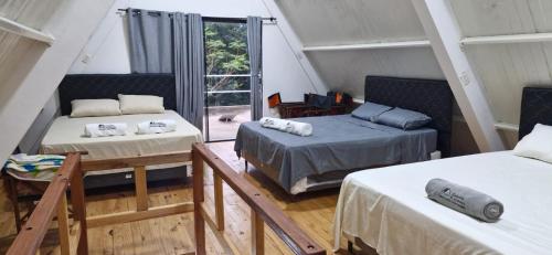 a attic room with two beds and a window at Cabaña El Dorado, Alojamiento in Puerto Cantera