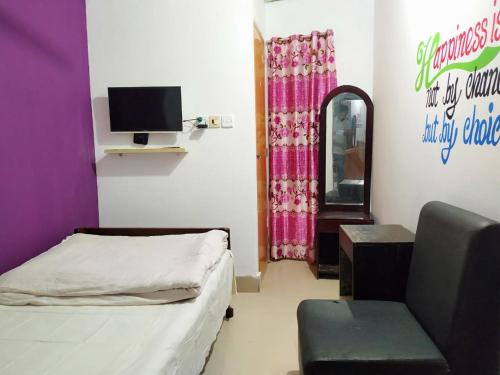 a room with a bed and a chair and a tv at International Dormitory Mohsin Plaza in Sreemangal