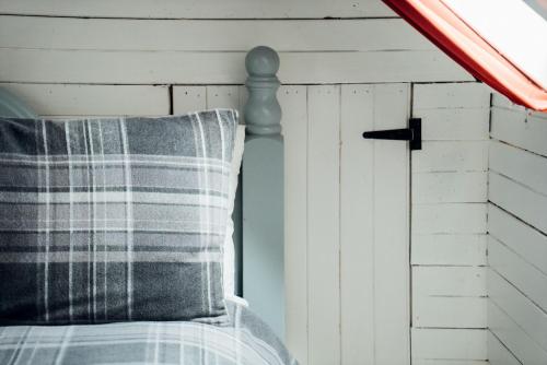 a bed with a striped pillow and a window at The Croft Collective in Oban
