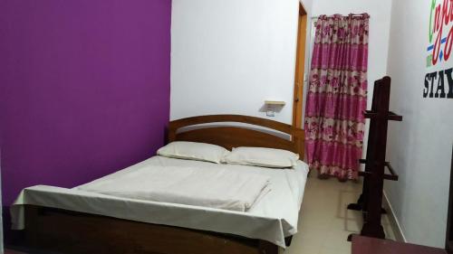 a small bed in a room with a purple wall at International Dormitory Mohsin Plaza in Sreemangal