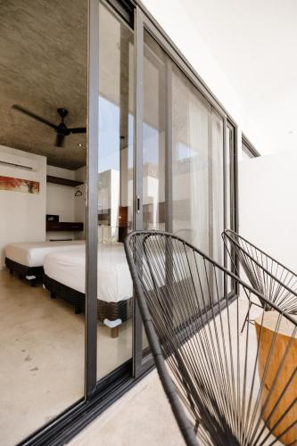 a bedroom with a bed and a glass wall at Hotel Zendero Tulum in Tulum