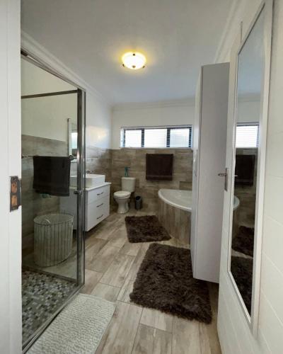 a bathroom with a tub and a toilet and a sink at Seashell Flat in Mossel Bay