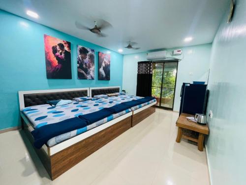 a bedroom with a large bed with blue walls at NS Dosti By Glitz Cottage in Agashi