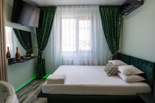 a bedroom with a bed with green curtains and a window at Elma Nest in Drobeta-Turnu Severin