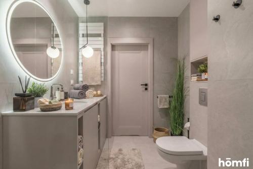 a bathroom with a sink and a toilet and a mirror at Libra Luxury AC - homfi Collection in Krakow