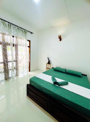 a bedroom with a large bed with green sheets at Footmark Surf Stay in Pottuvil