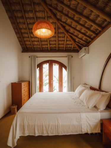 a bedroom with a large white bed with a large window at Villa Mia - Praia do Preá in Prea