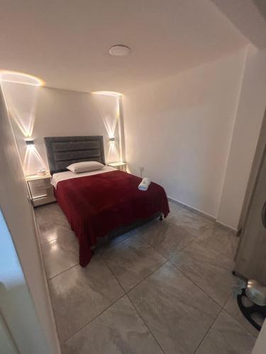 a bedroom with a bed with a red blanket and two lamps at Apartamento amoblado Chinchiná in Chinchiná