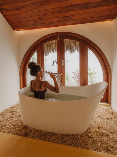 a woman brushing her teeth in a bath tub at Villa Mia - Praia do Preá in Prea