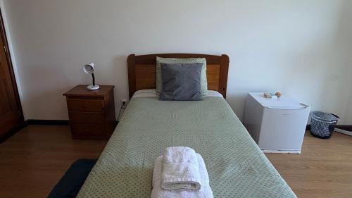 a bedroom with a bed with two towels on it at Quarto de Solteiro com varanda centro de Viseu in Viseu