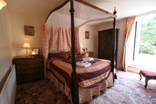 a bedroom with a four poster bed and a window at Staghunters Inn Hotel in Countisbury