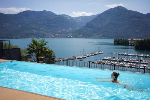 a woman in a swimming pool with a view of a lake at B&B Antenhofer Lovere in Lovere