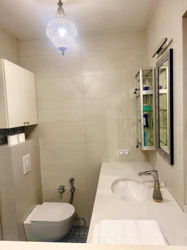 a bathroom with a sink and a toilet and a chandelier at Чарунки днів in Mukacheve