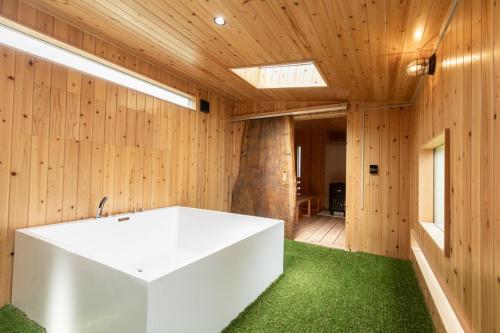 a bathroom with a white tub and wooden walls at 愛犬と泊まれる一棟貸しviilaはBBQグリル無料利用可能サーフィンや釣りの拠点として in Kashima